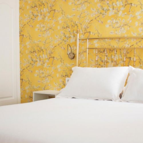 Foto de cama y estampado de la pared de la habitación amarilla