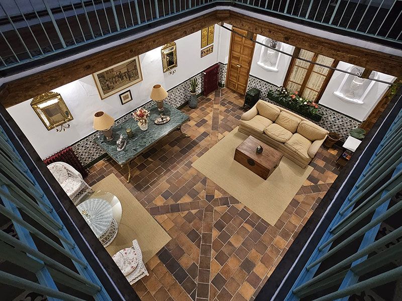 Patio interior con encanto antiguo, de dos niveles y barandilla de forja verde