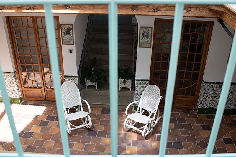 Detalle del patio al aire libre, blanco y adornado con butacas de mimbre que recrean la atmósfera histórica