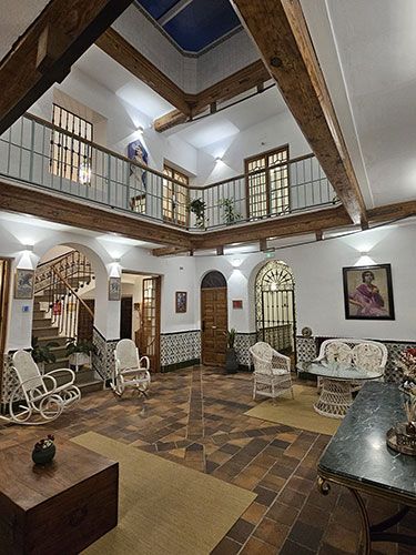Patio interior con estructura de dos niveles y barandilla de forja verde