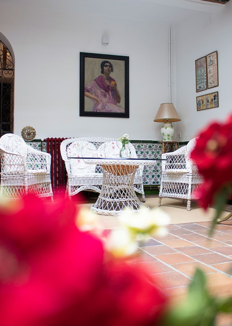 Ambiente flamenco rural del siglo XVIII en el patio exterior, con paredes blancas y muebles de mimbre